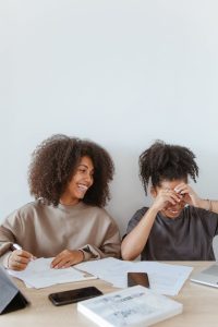 Two teenage girls enjoying a study session at home, laughing and smiling.